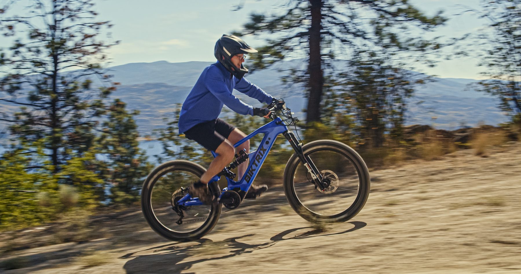 A rider on a Monte Capro climbing a dirt trail above a lake